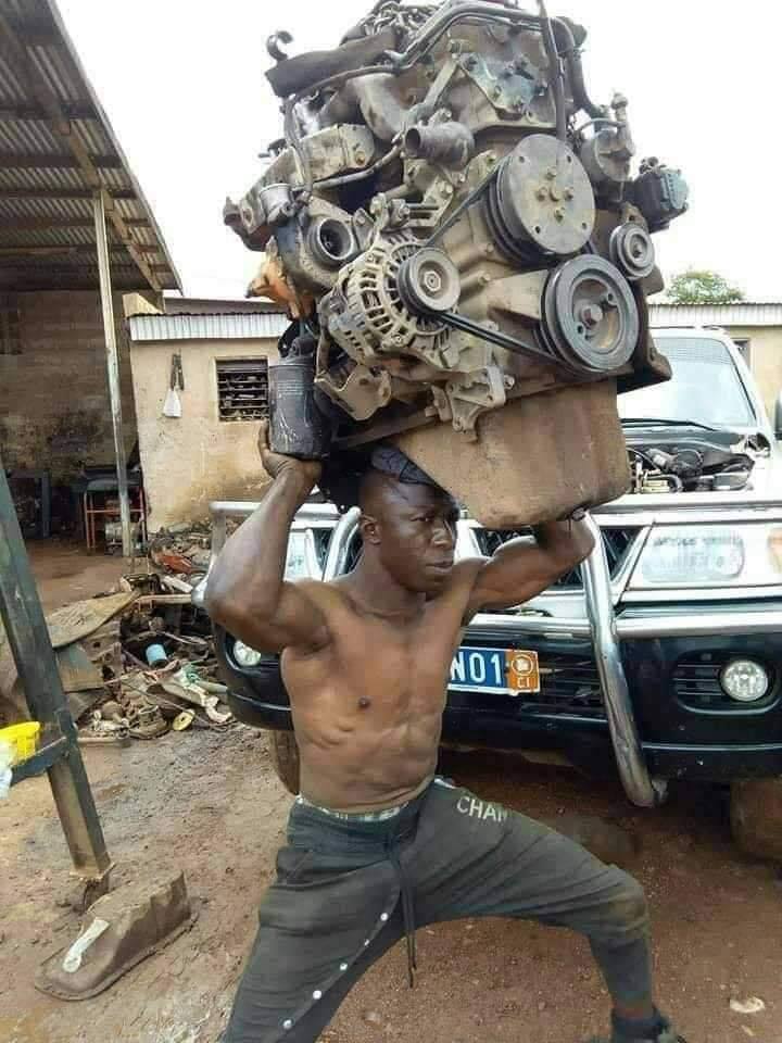 This meme features a photo of a person, presumably a man, lifting a massive weight, likely a car or a heavy machine, above their head. The image is captioned "I just spent 3 hours making a 10 minute workout".